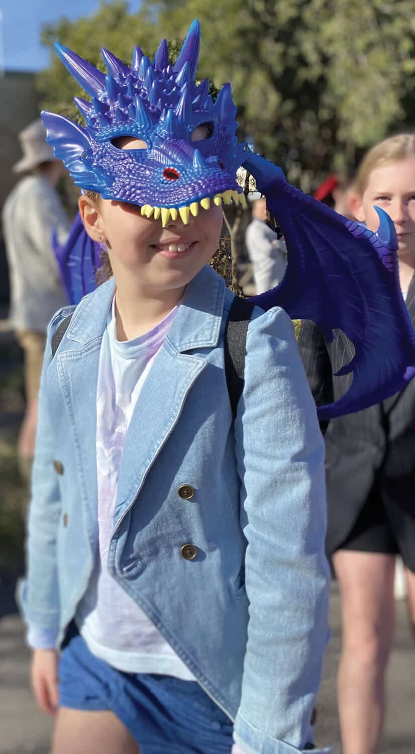 A girl wearing a blue dragon mask walking.