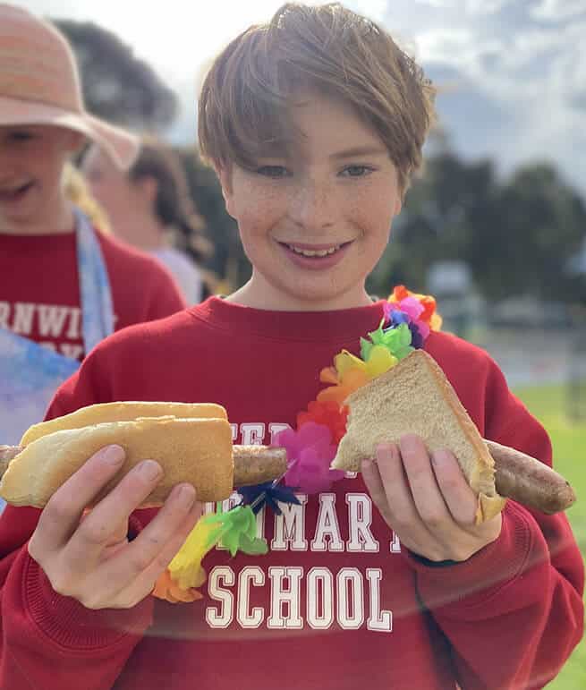 A boy holding two hot dogs.